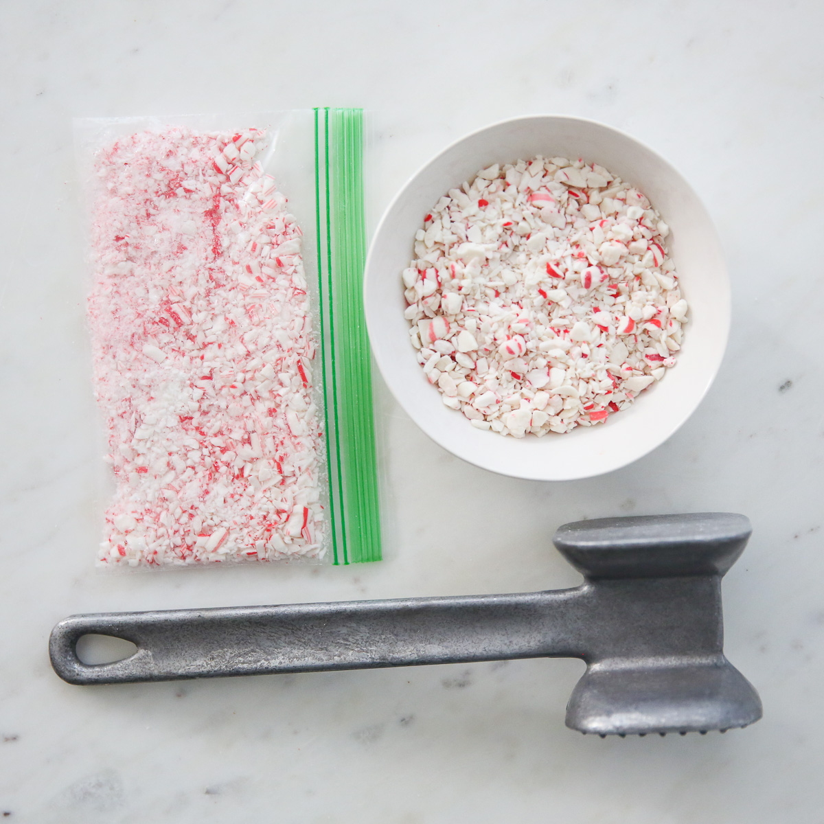 crushed candy canes in a bowl next to a mallet