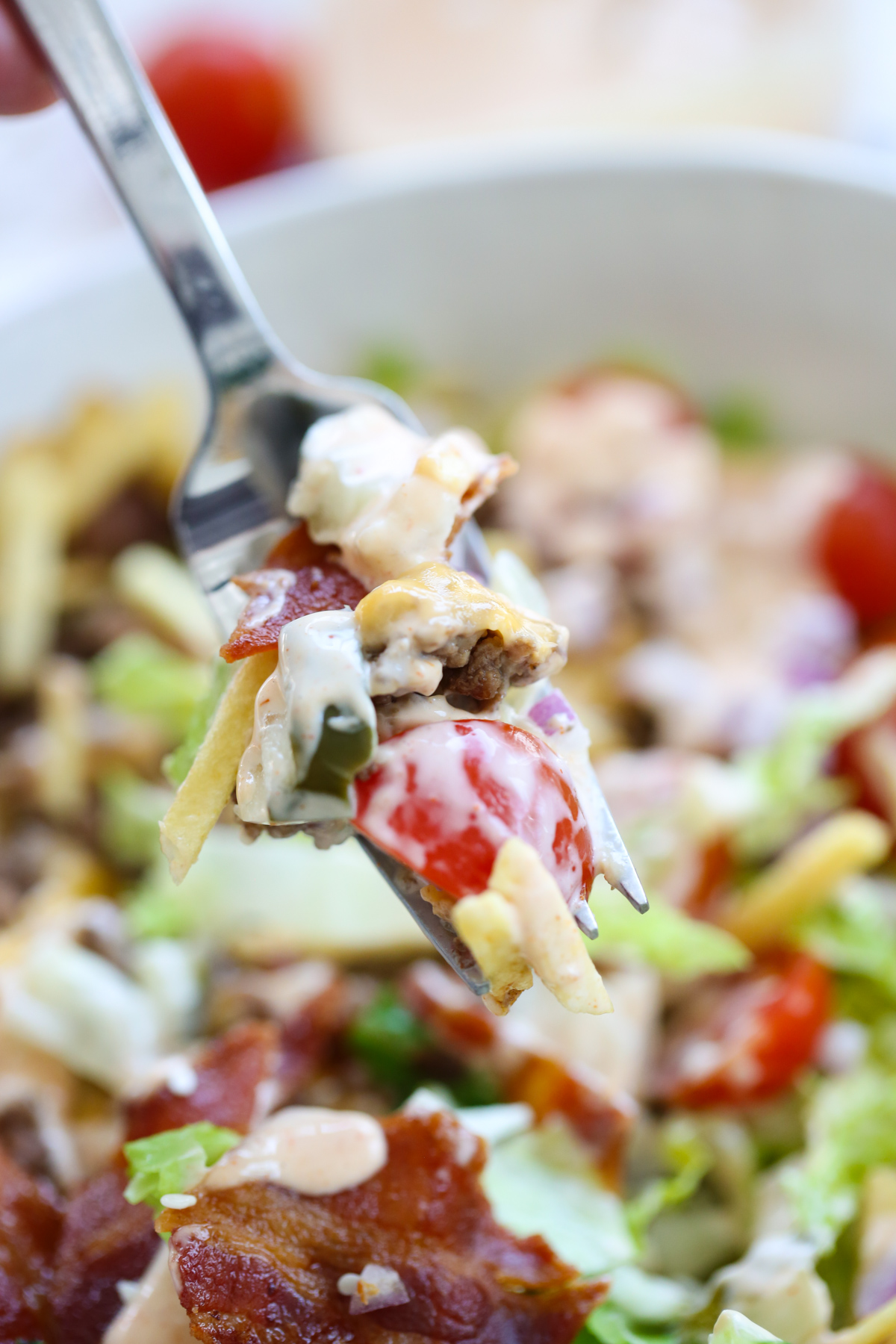 close up bite of a bacon cheeseburger salad bowl with all the toppings