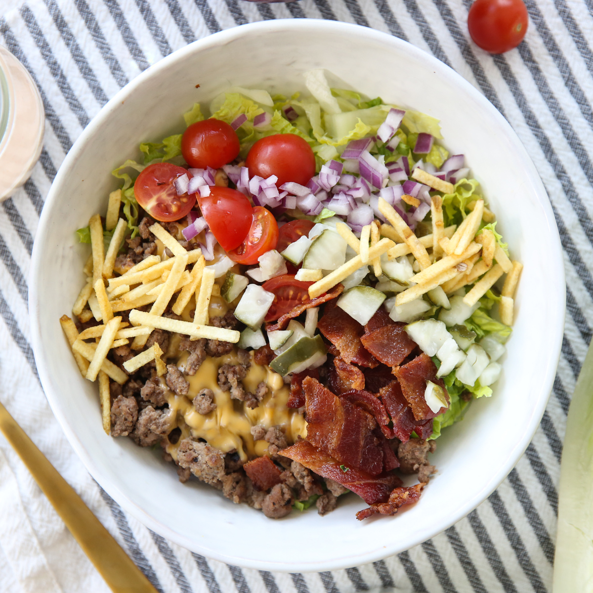 cheeseburger salad in a white bowl with lots of toppings