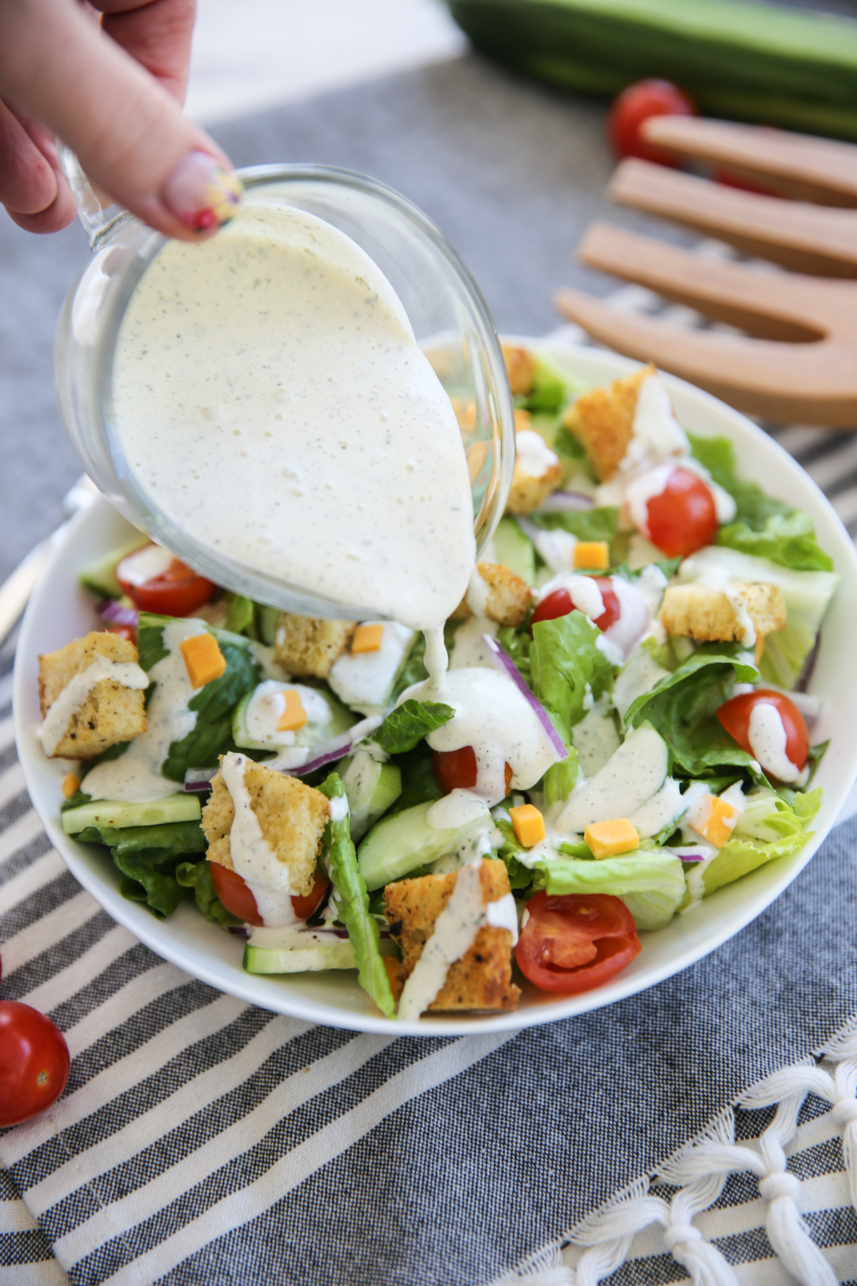 Pouring ranch dressing on a house salad