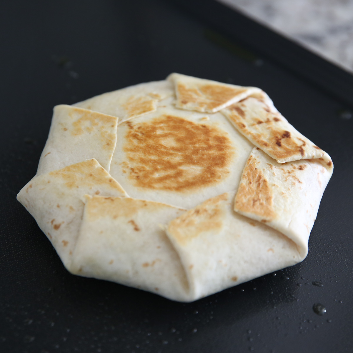 cooking a crunch wrap on a skillet