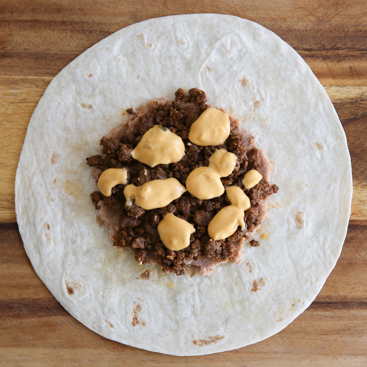 beans, meat, and cheese on a tortilla