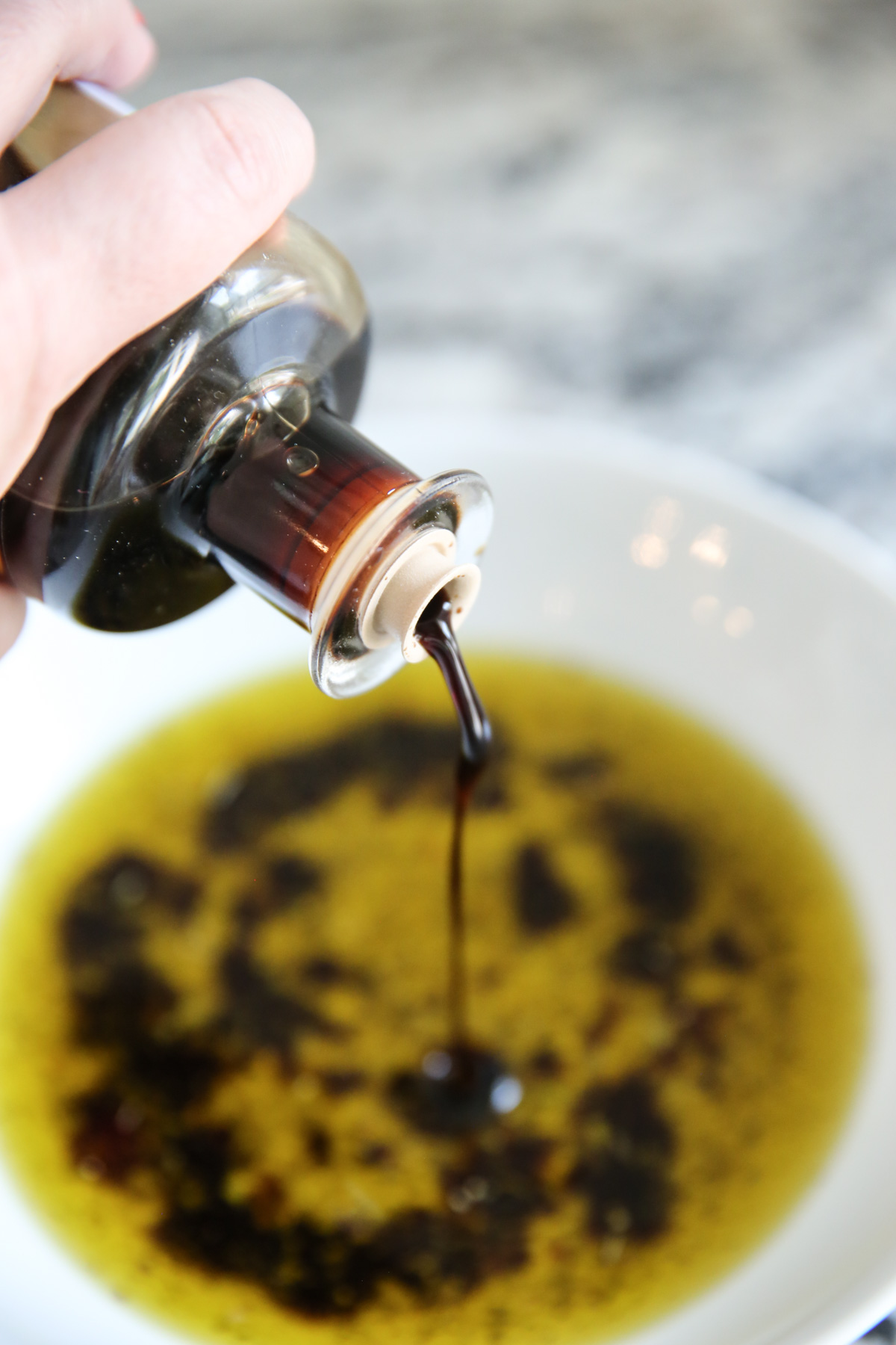 pouring balsamic vinegar over olive oil