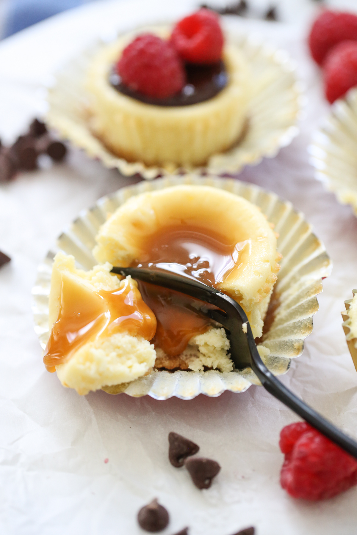fork cutting cheesecake with caramel sauce on top