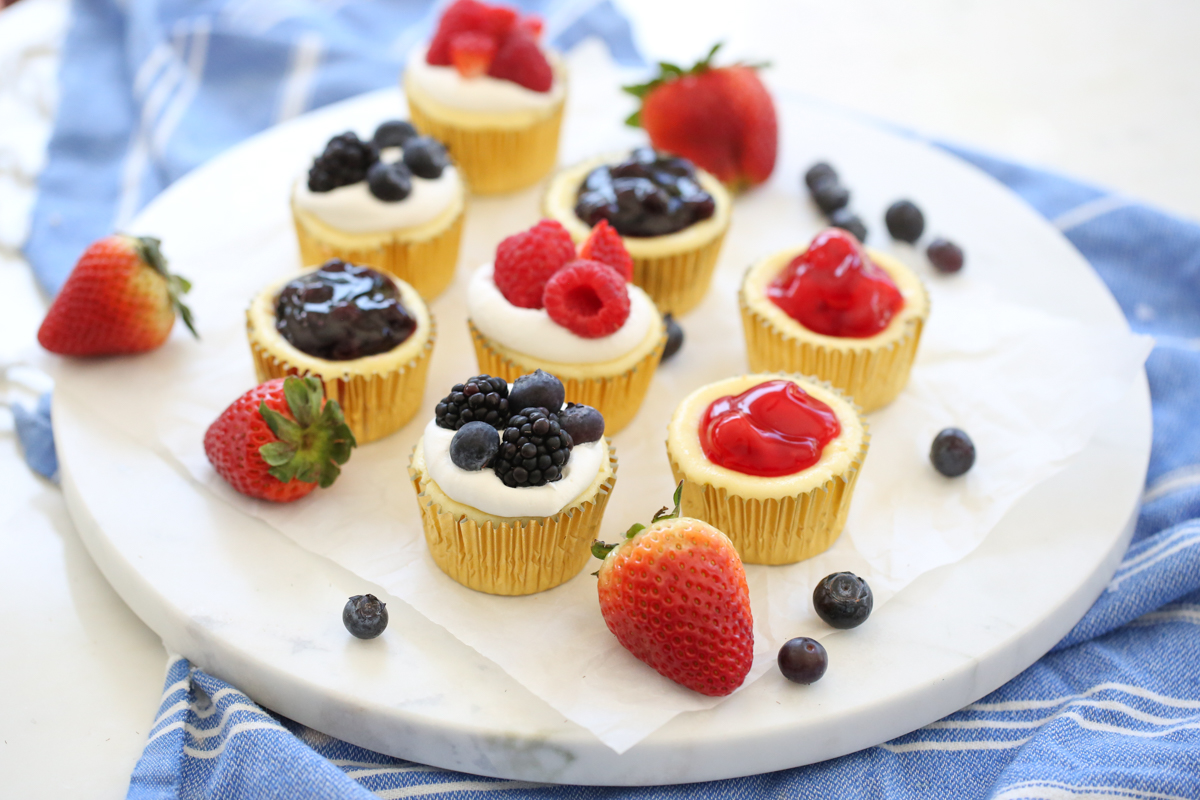 fruit topped mini cheesecakes on a platter
