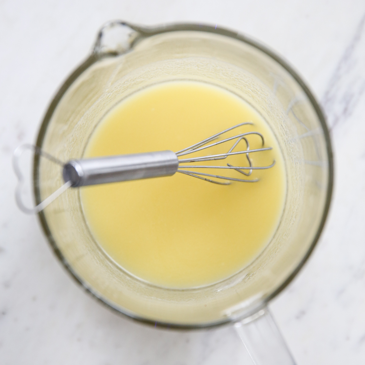 melted butter in a measuring cup with a whisk
