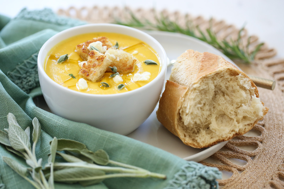 butternut squash soup in a bowl with a loaf of bread