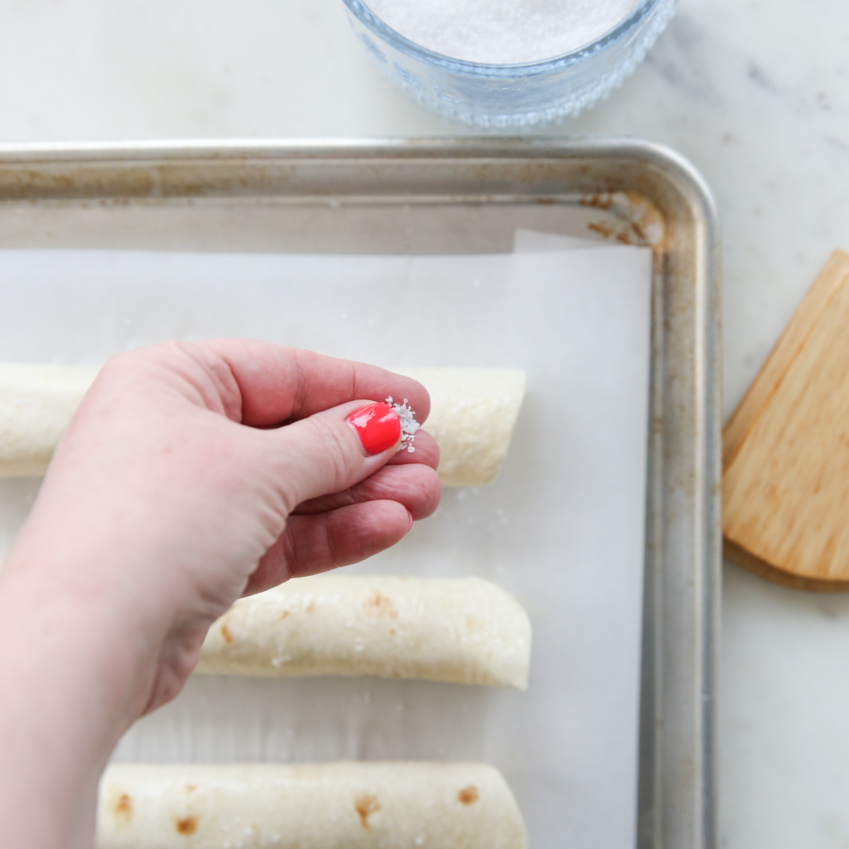 sprinkling salt on chicken taquitos
