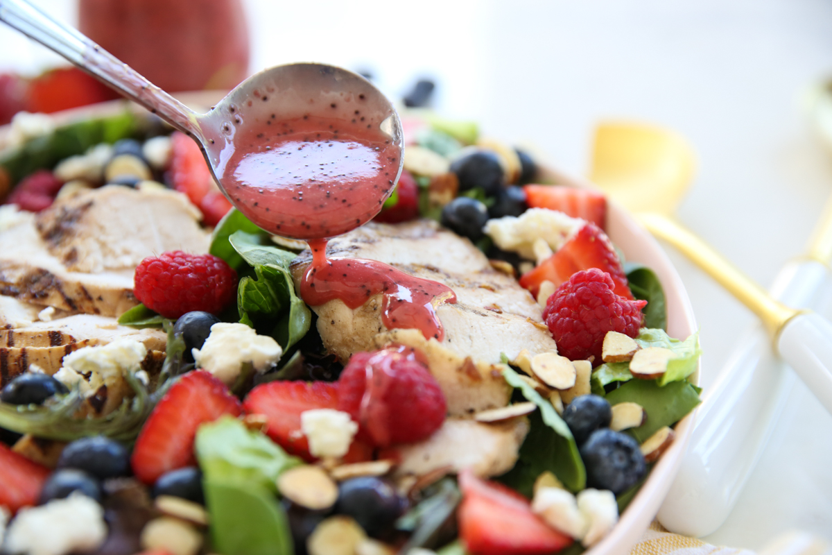 pouring berry dressing over salad

