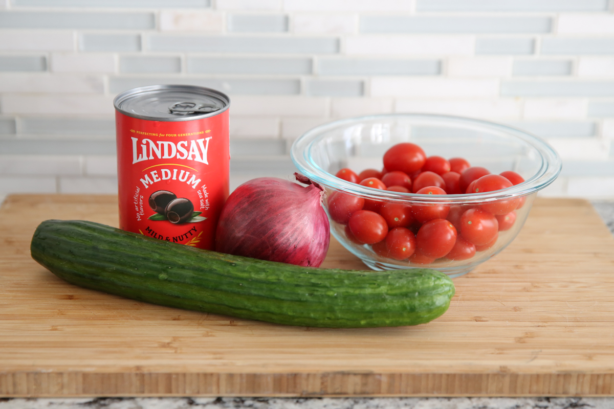 olives, red onion, cucumber and tomatoes on a cutting board