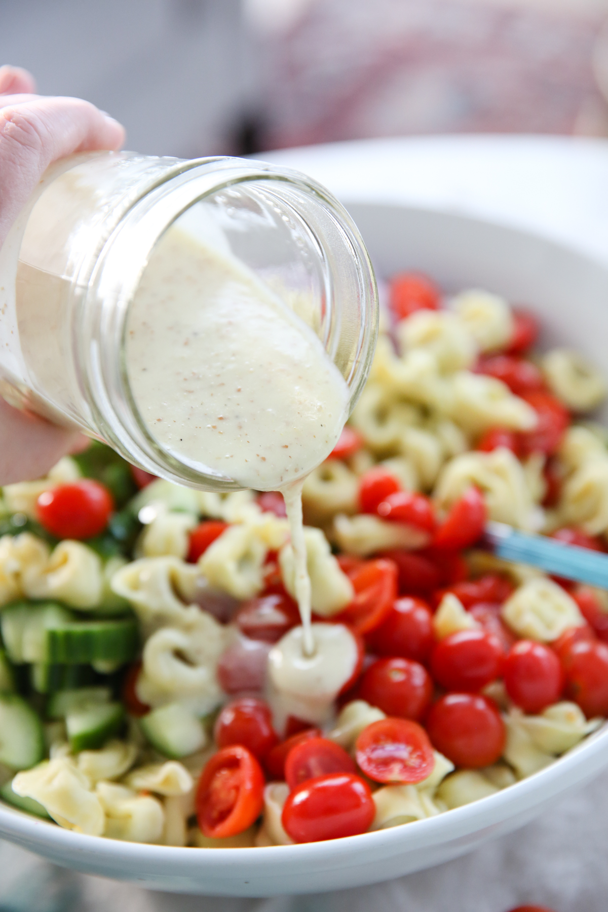 Pouring Mustard Vinaigrette over tortellini Salad