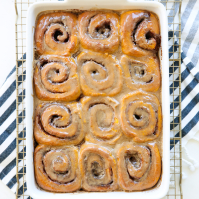 pumpkin spice cinnamon rolls in baking dish on towel