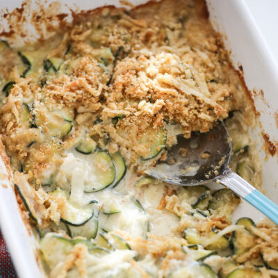 scooping zucchini gratin out of pan